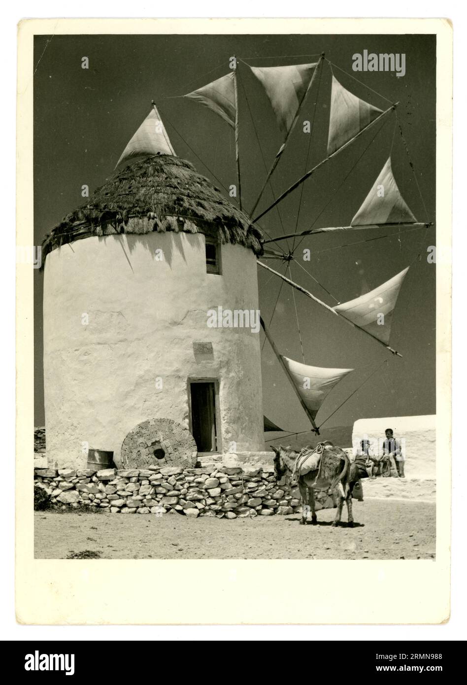 Original-Postkarte aus den späten 1950er Jahren, 1960er Jahre, als Andenken an eine Windmühle mit funktionierenden Segeln, die zum Mahlen von Weizen verwendet wird. Griechische Insel Mykonos, Kykladen, Griechenland, dieses Bild zeigt die letzten Arbeitsjahre dieser Windmühle. Die Windmühlen sind Wahrzeichen von Mykonos. Stockfoto