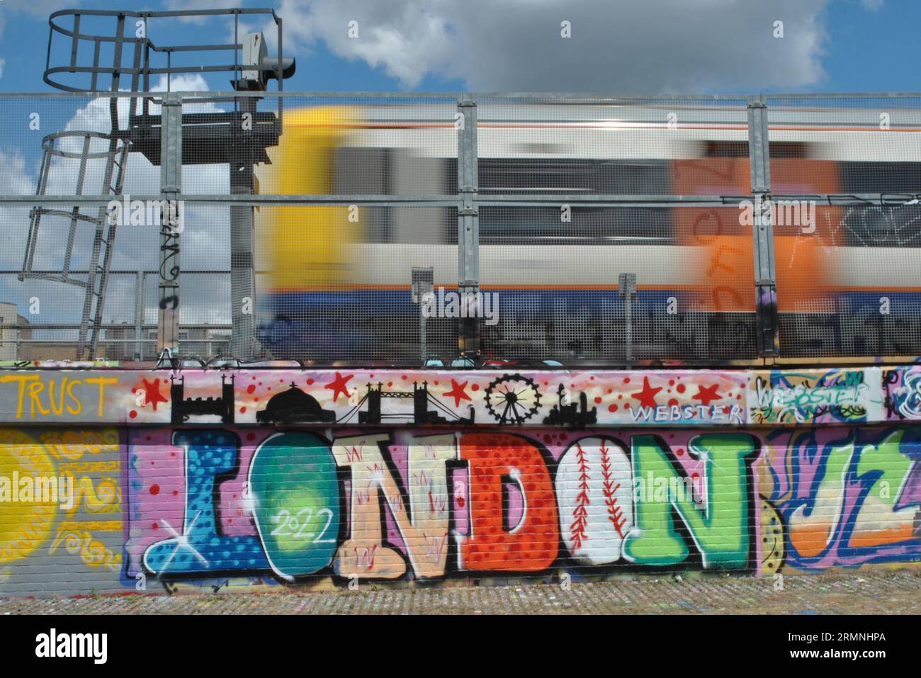 Das Wort London steht in Graffiti-Buchstaben neben einem vorbeifahrenden London Overground-Zug in Shoreditch East London Stockfoto