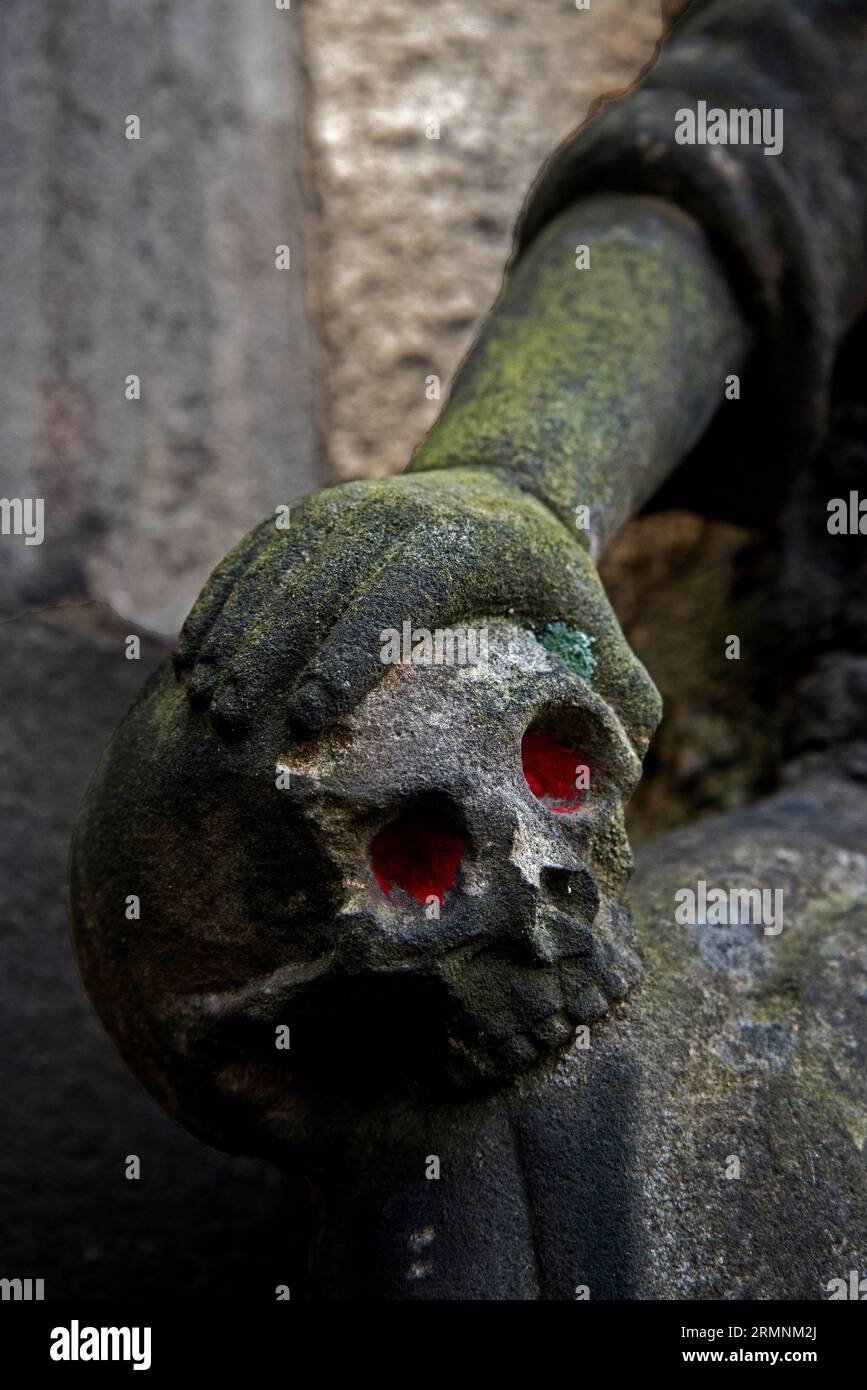 Eine Hand, die einen Schädel mit roten Augen hält, Details aus einer Gedenkstätte in Greyfriars Kirkyard in Edinburgh. Stockfoto