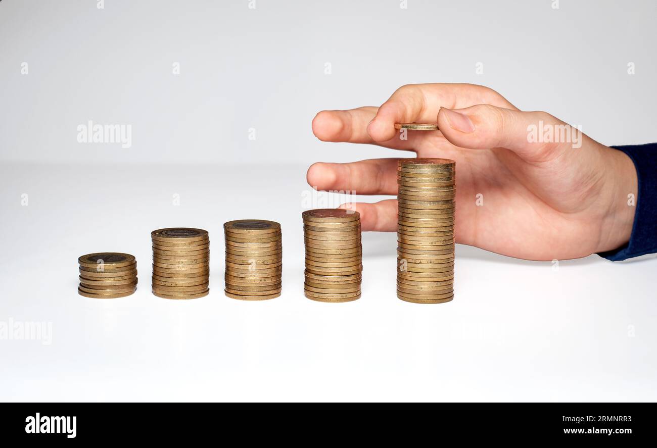 Hand mit Münzstapel. Konzept für finanzielle Wachstumseinsparungen. Sparen Sie Geld durch die manuelle Verwendung von Münzen Geld Buchungsplanung. Stockfoto