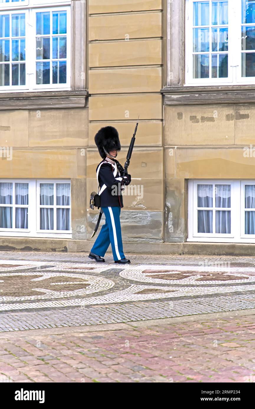 Eine königliche Garderin in eleganter königlicher Rettungswache führt mit einem Gewehr durch das Schloss Amalienborg, das Wahrzeichen von Kopenhagen Stockfoto