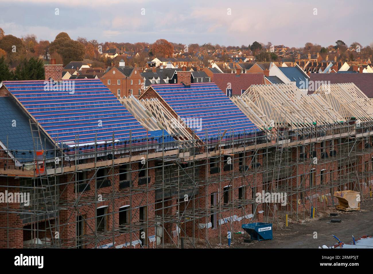 Neues Wohneigentum in verschiedenen Stadien der Fertigstellung: Eine Reihe von Häusern, teilweise gefertigte Dächer mit Sparren, Pfetten, Latten und Membranen. Stockfoto