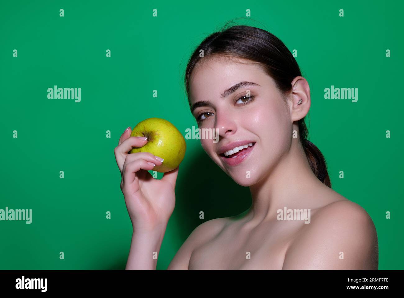 Das beißende Apfelkonzept. Porträt einer jungen Frau, die Apfel isst, isoliert im Studiohintergrund. Gesunde Apfelfrucht, natürliches Vitamin, Diät und vegan Stockfoto