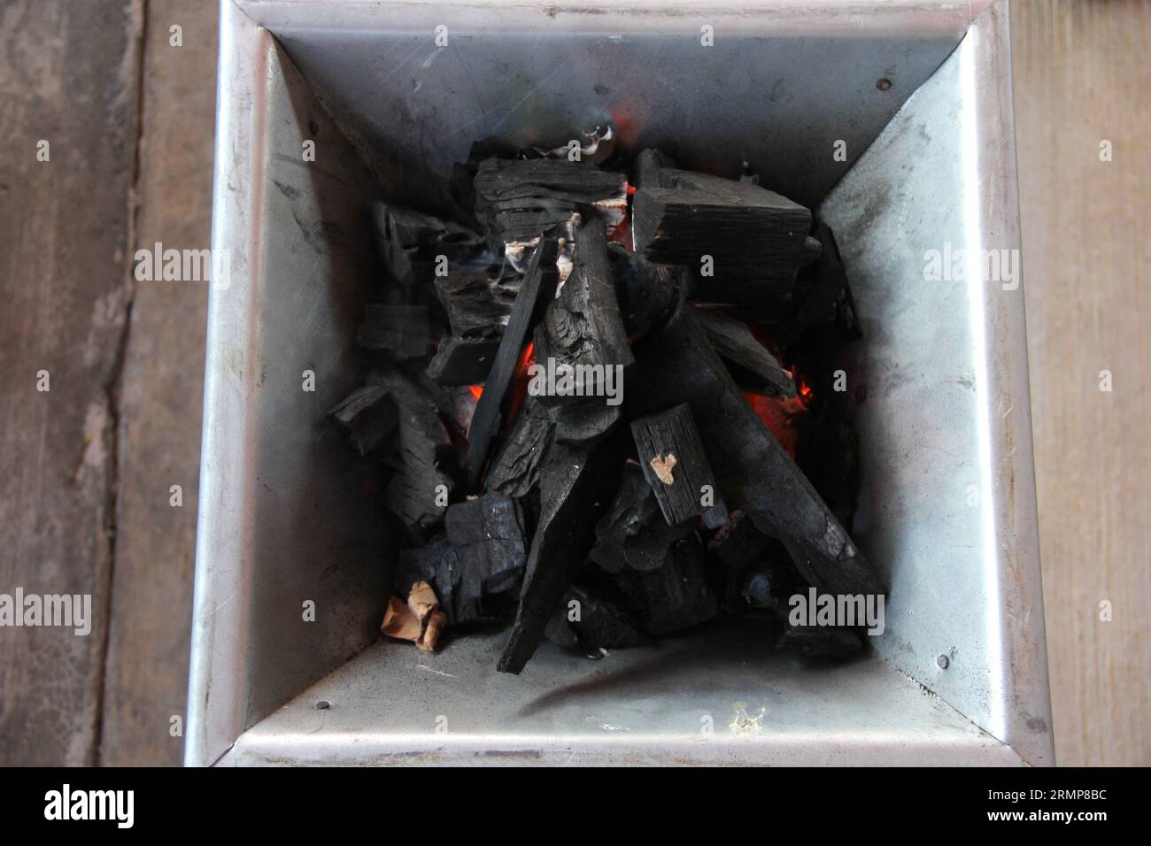 Holzkohlestücke auf einem Grillherd, die ein Feuer zum Kochen oder Braten von Fleisch anzünden Stockfoto