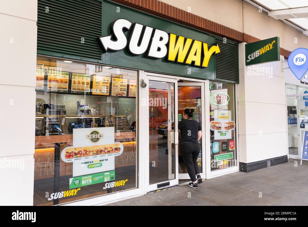 Eine Frau, die in einem U-Bahn-Restaurant zum Mitnehmen in Chelsea, London, Großbritannien, spaziert. Subway ist ein amerikanisches Fast-Food-Restaurant Stockfoto
