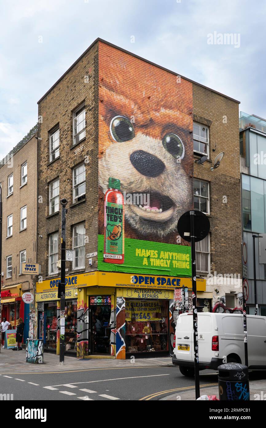 Ein riesiges Wandgemälde eines riesigen Bärenkopfes, das Teds heiße Sauce in einem Backsteingebäude an der Ecke von Brick Lane und Bacon Street, London, Großbritannien, anpricht Stockfoto