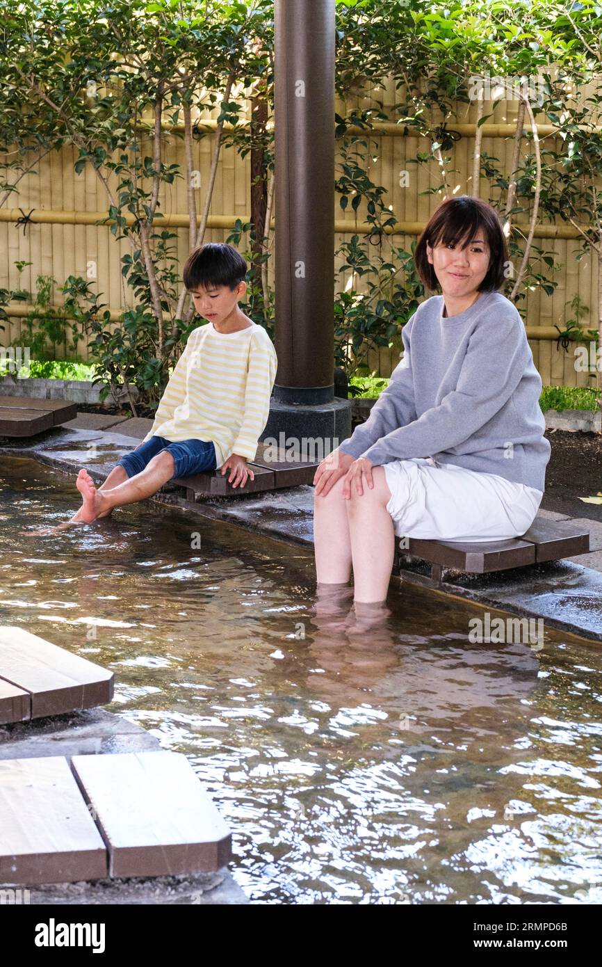 Japan, Kyushu, Beppu. Mutter und Sohn tränken die Füße im öffentlichen Fußdampfbad. Stockfoto