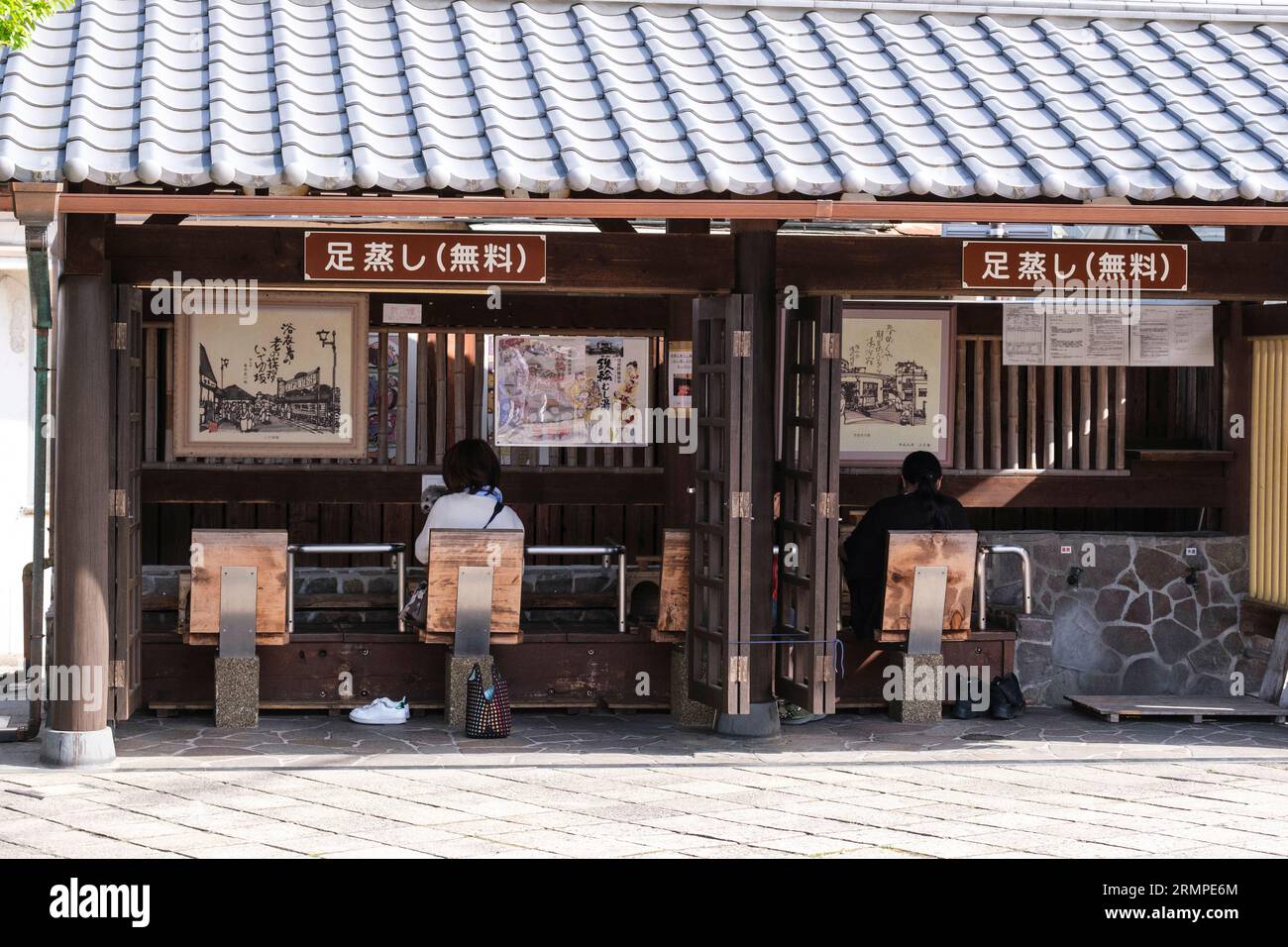 Japan, Kyushu, Beppu. Personen, die die Füße in einem kostenlosen öffentlichen Fußbad genießen. Stockfoto