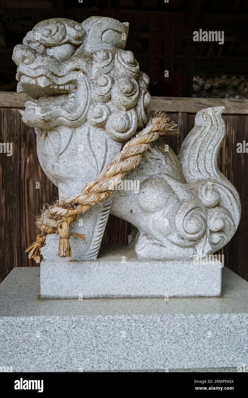 Japan, Kyushu. Löwenhund-Wächter im buddhistischen Tempel Tennen-JI und Shinto-Schrein. Das Shimenawa-Seil weist auf einen heiligen oder rituell reinen Raum hin. Stockfoto