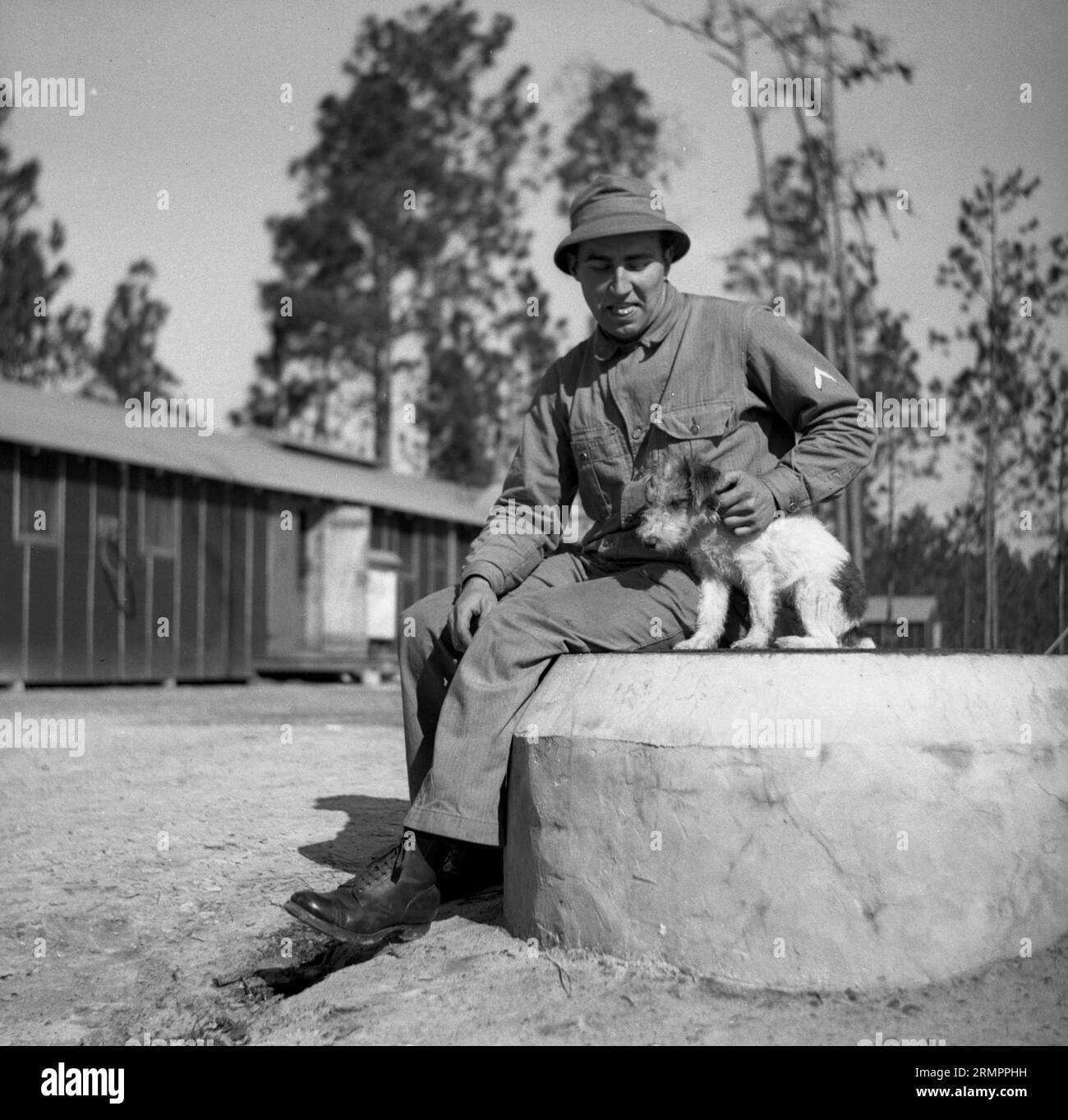 Solider mit Hund posiert für ein Foto. Mitglieder der 114. Infanteriedivision der US-Armee trainieren im Zweiten Weltkrieg gegen Deutschland in Europa. Stockfoto