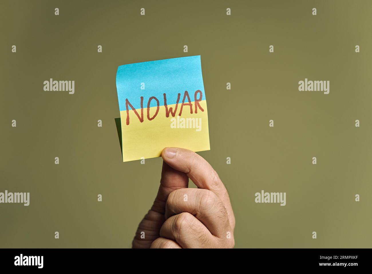 Die Hand des Mannes hält einen Aufkleber in Form einer ukrainischen Flagge mit der Aufschrift kein Krieg Stockfoto