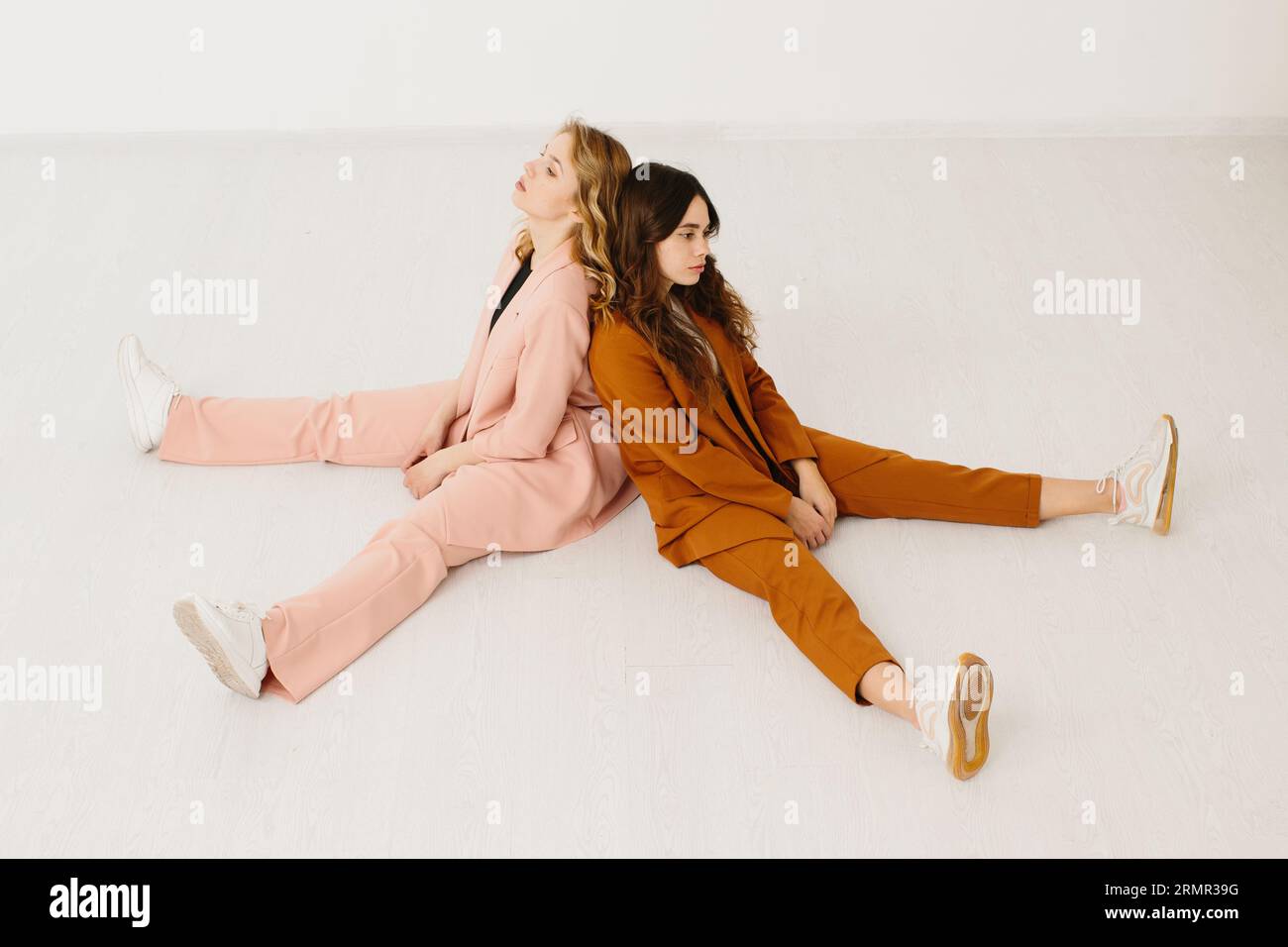 Moderne junge Frauen in modischen Pastellanzügen mit unknöpfbarem Blazer auf weißem Hintergrund. Stockfoto