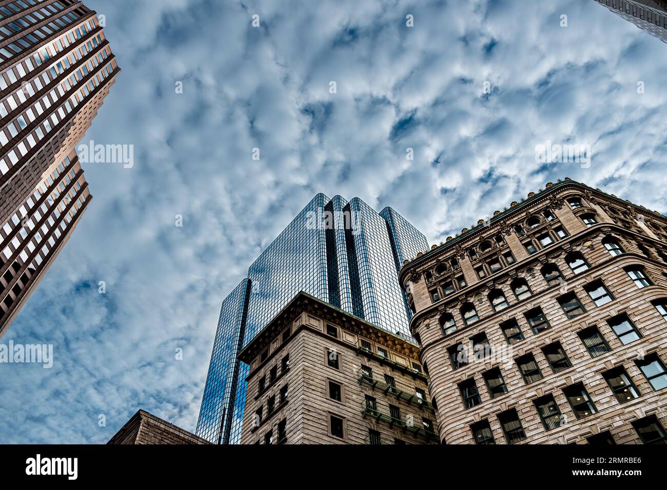 Der Skyscrapr des Exchange Place erhebt sich über den älteren Gebäuden, die ihn umgeben, mit dem blauen Himmel und der gebrochenen Wolke, die vom Gebäude reflektiert wird Stockfoto