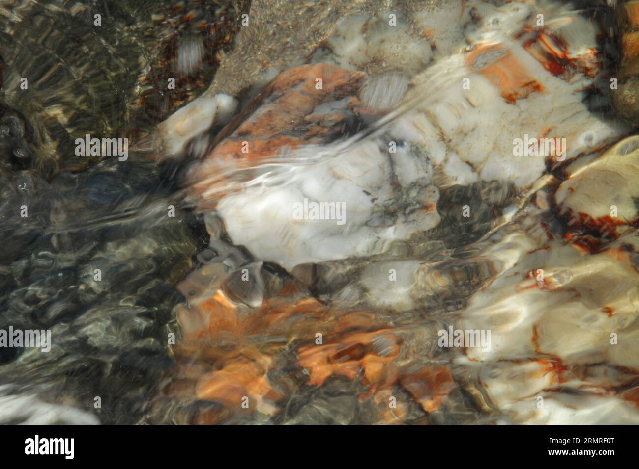 Weiße, graue und rötlich braune Felsen unter Wasser Stockfoto