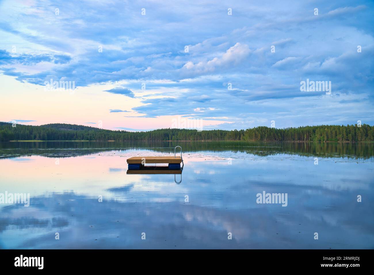 Schwimmende Insel in Schweden auf einem See bei Sonnenuntergang. Wolken spiegeln sich im Wasser. Schwimmspaß im Urlaub mit Erholung in Skandinavien Stockfoto