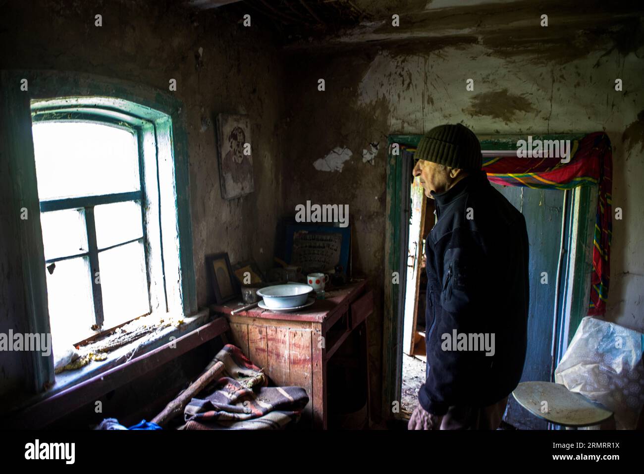 Ein alter Mann, in der Nähe eines Fensters in seiner verlassenen Hütte Stockfoto