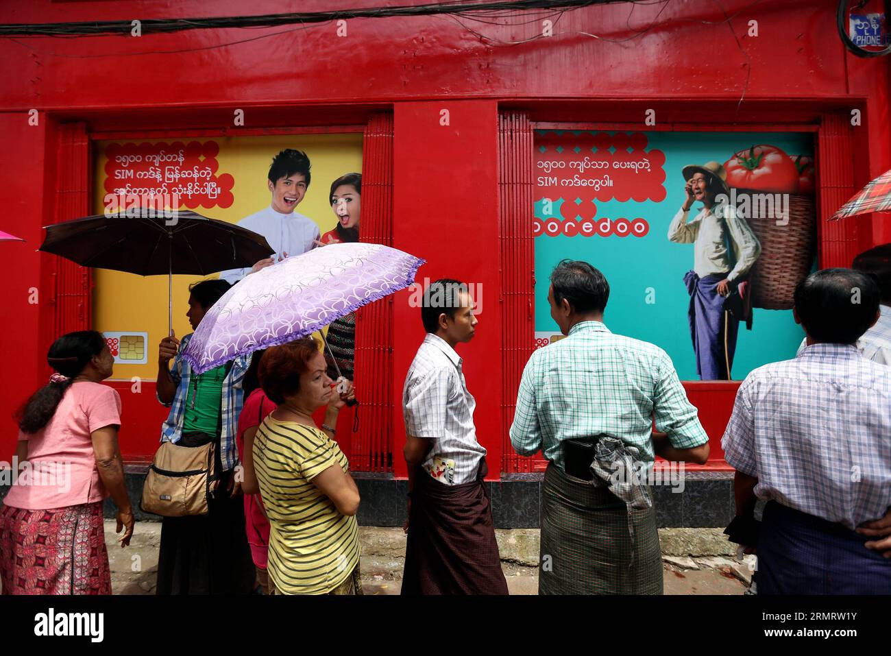 Die Leute warten auf den Kauf einer kostengünstigen Ooredoo SIM-Karte vor einem SIM-Kartenverkauf in Yangon, Myanmar, 4. August 2014. Ooredoo Myanmar, die lokale Einheit des in Katar ansässigen Telekommunikationsbetreibers, begann am 2. August in drei myanmarischen Städten mit dem Verkauf preiswerter SIM-Karten, während die Regierung die Mobilfunkabdeckung in Myanmar verbessern wollte. ) MYANMAR-YANGON-OOREDOO-BILLIGE SIM-KARTE UxAung PUBLICATIONxNOTxINxCHN Prominente warten auf den Kauf einer billigen SIM-Karte außerhalb eines SIM-Kartenverkaufsgeschäfts in Yangon Myanmar 4. August 2014 Myanmar die lokale Einheit des in Katar ansässigen Telekommunikationsbetreibers begann, billige SIM-Karten in zu verkaufen Stockfoto