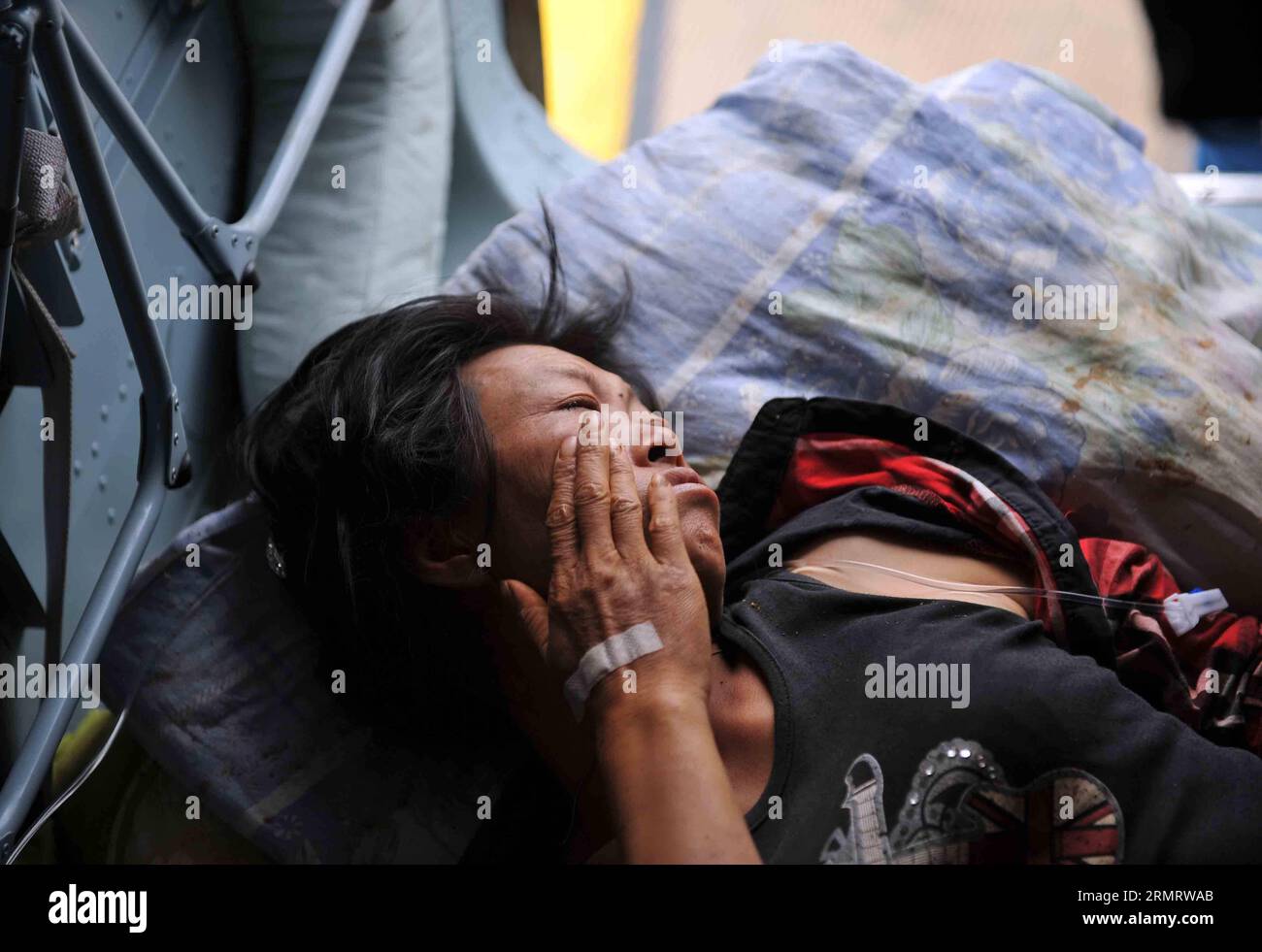 Eine Frau, die bei einem Erdbeben von 6,5 Magnitude verletzt wurde, wartet auf die Überführung in die Stadt Zhaotong auf dem Luftweg in der Stadt Longtoushan unter dem Ludian County von Zhaotong, südwestchinesische Provinz Yunnan, 4. August 2014. Die Stadt Longtoushan ist das Epizentrum des Bebens, das am Sonntag um 16:30 Uhr (Pekinger Zeit) in einer Tiefe von 12 km einschlug Am Montag um 14 Uhr hat das Beben 398 Menschen getötet und 1.801 verletzt, während mehr als eine Million andere in Zhaotong und Qujing betroffen waren. ) (lmm) CHINA-YUNNAN-LUDIAN-EARTHQUAKE-EPIZENTRUM (CN) XuexYubin PUBLICATIONxNOTxINxCHN eine Frau, die sich in einer 6 5 Magni verletzt hat Stockfoto