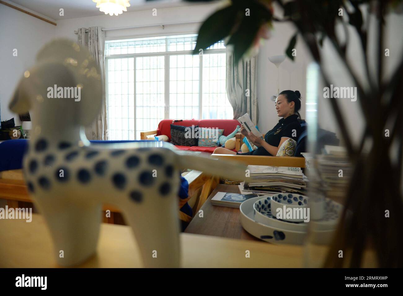 (140806) -- PEKING, 6. August 2014 -- Zhang Lingyun liest ein Buch in ihrem Haus in Jingdezhen, Ostchinesische Provinz Jiangxi, 17. Juli 2014. Yoga und Lesen sind Zhangs Hobbys abseits der Arbeit. Zhang Lingyun ist 40. Es ist 20 Jahre her, dass der Keramikkünstler nach Jingdezhen kam, Chinas Porzellanhauptstadt. Zhangs Geschichte mit Keramik hatte einen zufälligen, romantischen Anfang: Sie wusste kaum etwas über Keramik, bevor sie bei der Bewerbung für das College auf den Namen Jingdezhen Ceramic Institute (JCI) stieß. Keramik klang interessant, also reichte ich den Antrag für JCI ein. Die Laune des Impulses hatte eine große Verschiedenheit hervorgerufen Stockfoto