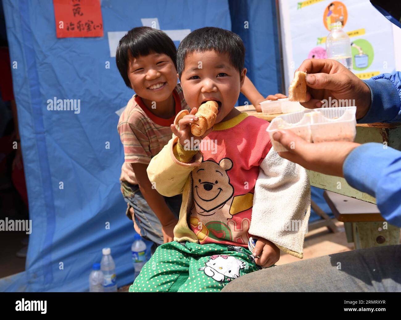 (140806) -- LUDIAN COUNTY, 6. August 2014 -- Ein Kind isst Ein Stück Brot in einer provisorischen Siedlung, die nach einem Erdbeben von 6,5 Magnitude im Ludian County von Zhaotong, südwestlich der chinesischen Provinz Yunnan, 6. August 2014 gegründet wurde. Nach dem Erdbeben in Yunnan am Sonntagnachmittag werden derzeit Katastrophenhilfe geleistet. Civillians in provisorischen Siedlungen in den am stärksten betroffenen Gebieten hatten bereits Zugang zu frischem Essen und Trinkwasser. ) (lmm) CHINA-YUNNAN-ERDBEBEN-RETTUNG-KATASTROPHENHILFE (CN) LinxYiguang PUBLICATIONxNOTxINxCHN County 6. August 2014 ein Kind isst ein Stück BROT im Sturm Stockfoto