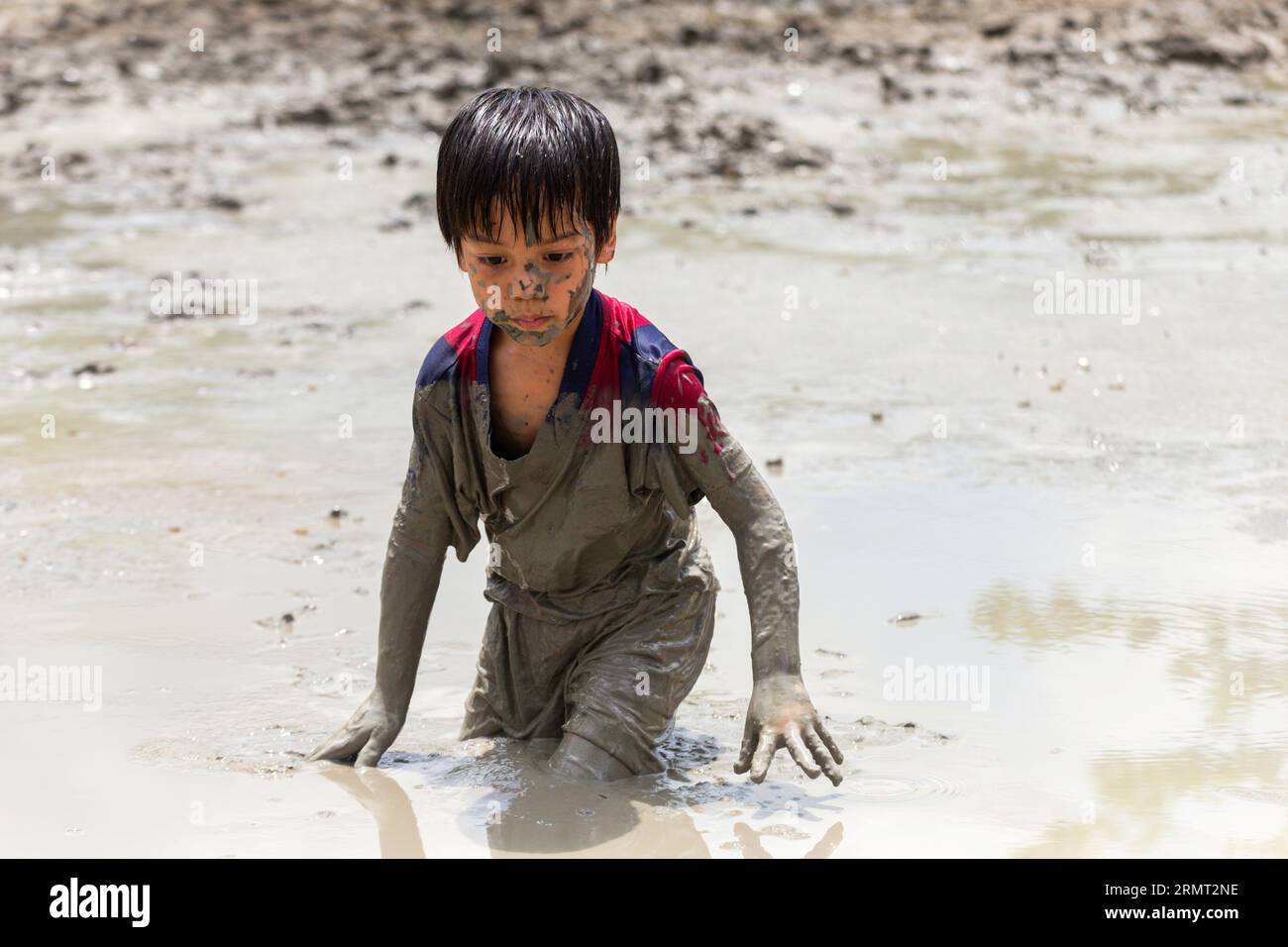 Süßer, glücklicher kleiner asiatischer Junge, der gerne im Schlamm auf dem Spielplatz spielt. Kindererziehung in der Natur an der montessori-Schule. Natur- und Bildungskonzept. Stockfoto