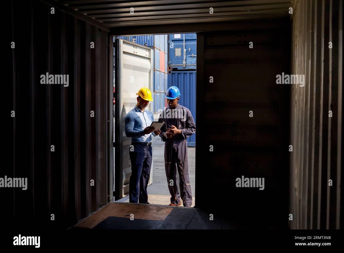 Lagerbetriebsleiter und Hafenarbeiter, die Container nach dem Verladen im Handelshafen bearbeiten und überprüfen. Logistik, Transport, Import und Export Stockfoto