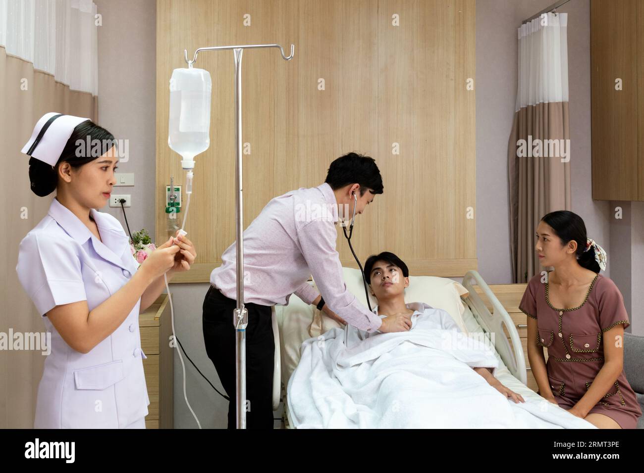 Krankenschwester, die Arzneimittel in den Infusionsschlauch injiziert, um den Patienten im Krankenhaus zu behandeln. asiatischer Arzt mit Stethoskop, der Herzschlag des Patienten hört. Gesundheitsauto Stockfoto