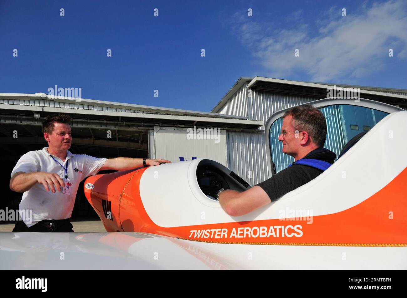 (140827) -- SHENYANG, 27. August 2014 -- Peter Wells (L), der mit dem Twister-Kunstflugteam zusammenarbeitet, diskutiert technische Probleme mit seinem Partner Guy Westagate in Shenyang, der Hauptstadt der Provinz Liaoning im Nordosten Chinas, 25. August 2014. Die Twister, ein britisches Kunstflugteam, machte ihre erste Stunt-Performance in China bei der Eröffnungszeremonie der Shenyang Faku International Flight Convention 2014, einer Flugshow, am 27. August. Der Twister wurde 2010 von Peter Wells gegründet, der aus einer Segelfamilie stammt. Guy Westgate, einer der Partner von Wells, ist auch Passagierflugzeugpilot der British Airways Stockfoto