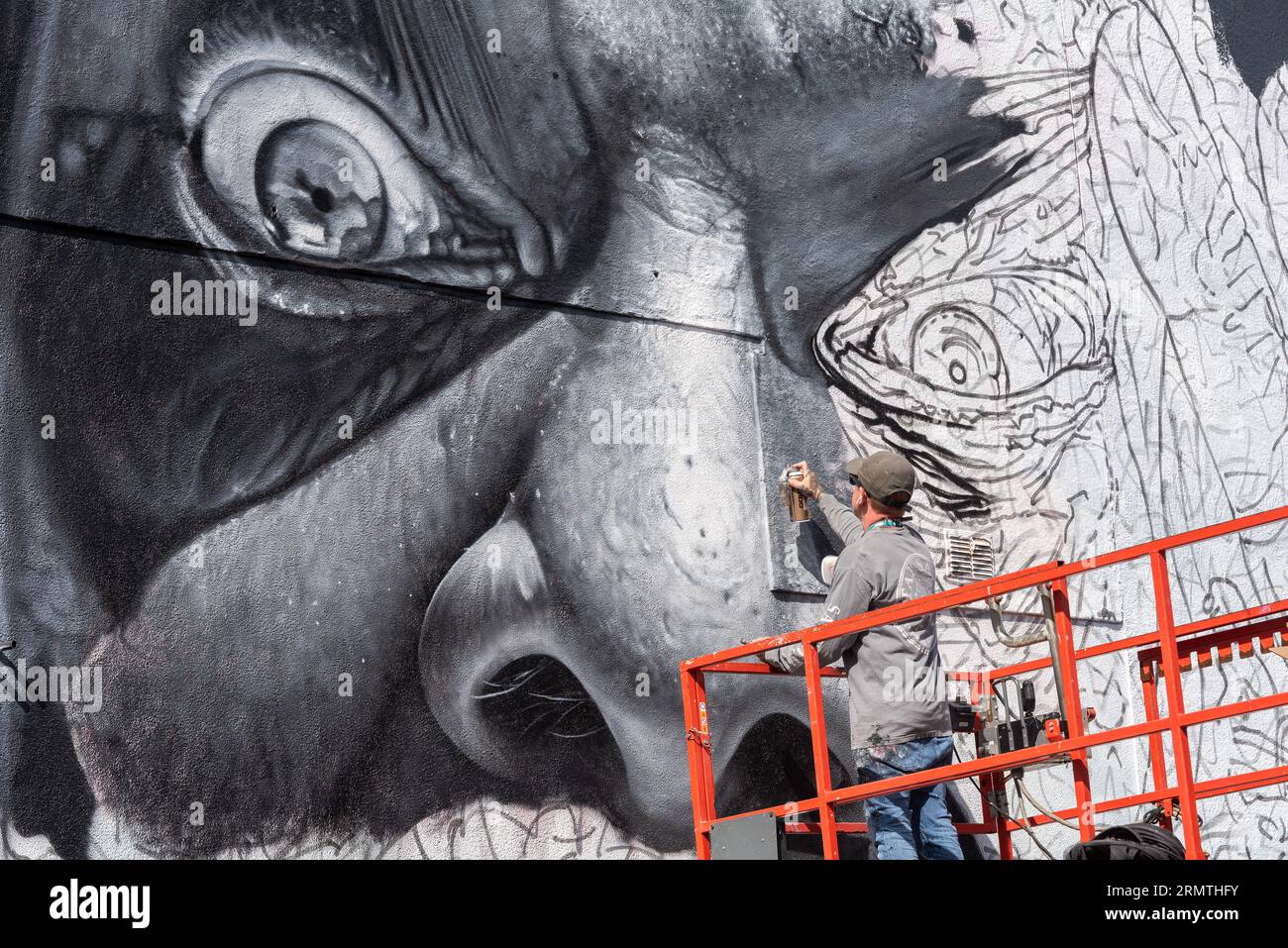 Southend on Sea, Essex, Großbritannien. 30. August 2023. Southend, das als Europas größtes Street-Art-Festival bezeichnet wird, feiert mit dem City Jam-Event seinen neuen Stadtstatus weiter. Über 200 lokale, nationale und internationale Straßenkünstler zeigen ihre Fähigkeiten an 100 Orten im Stadtzentrum. Einige provisorische Mauern wurden errichtet, aber die Künstler schmücken auch die Seiten von Gebäuden und andere dauerhafte Strukturen. Vom ersten bis zum dritten September haben die Künstler mit der Arbeit an den größeren Wandgemälden begonnen, um für die Veranstaltung bereit zu sein. Männlicher Künstler, der an grossen Fototapeten arbeitet Stockfoto