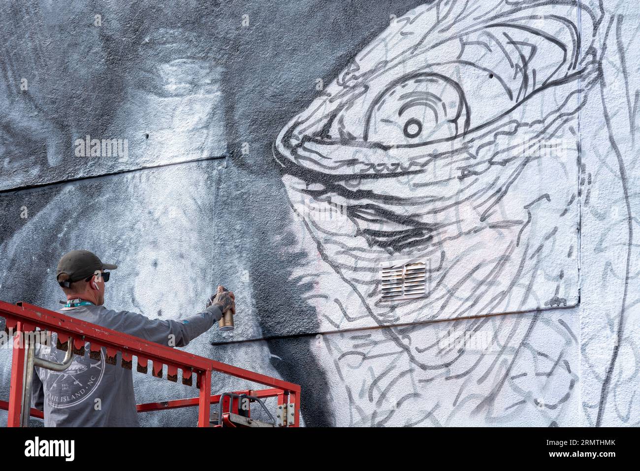 Southend on Sea, Essex, Großbritannien. 30. August 2023. Southend, das als Europas größtes Street-Art-Festival bezeichnet wird, feiert mit dem City Jam-Event seinen neuen Stadtstatus weiter. Über 200 lokale, nationale und internationale Straßenkünstler zeigen ihre Fähigkeiten an 100 Orten im Stadtzentrum. Einige provisorische Mauern wurden errichtet, aber die Künstler schmücken auch die Seiten von Gebäuden und andere dauerhafte Strukturen. Vom ersten bis zum dritten September haben die Künstler mit der Arbeit an den größeren Wandgemälden begonnen, um für die Veranstaltung bereit zu sein. Männlicher Künstler, der an grossen Fototapeten arbeitet Stockfoto