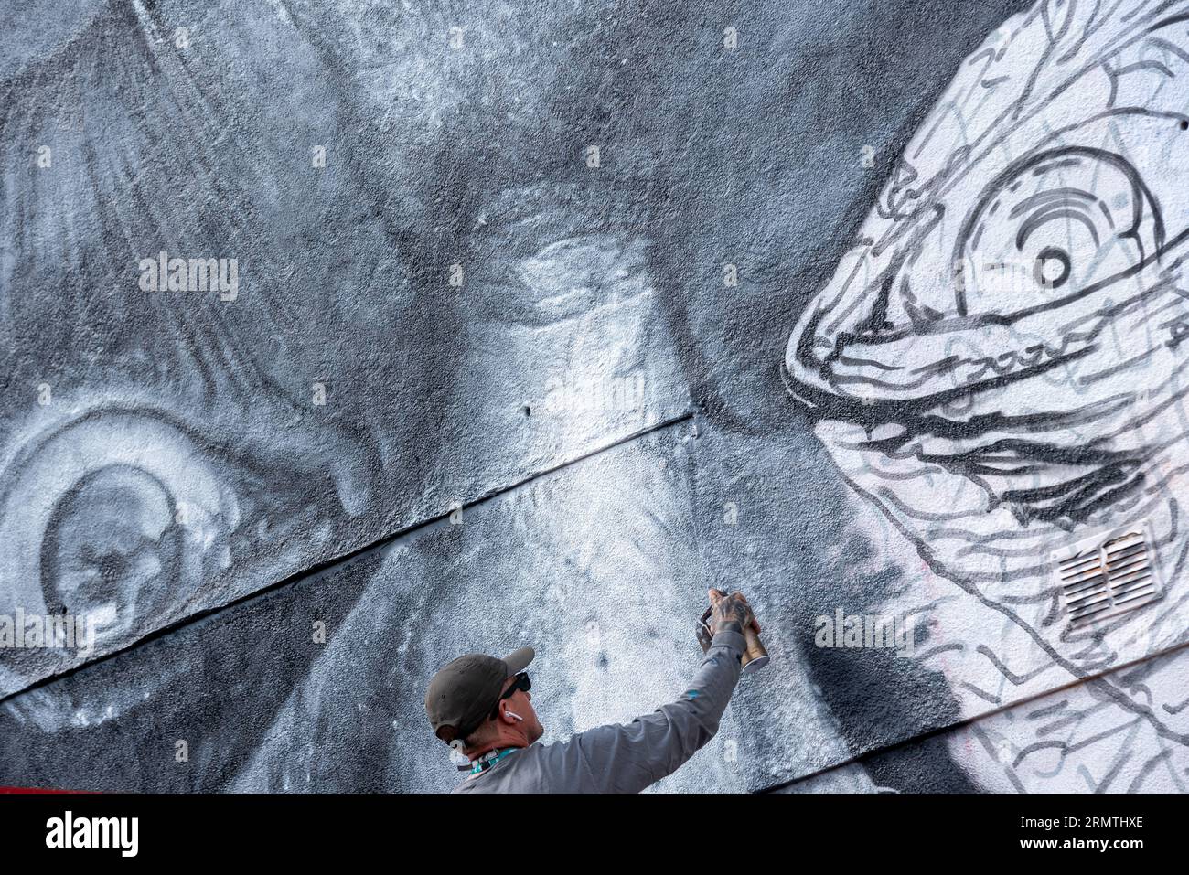 Southend on Sea, Essex, Großbritannien. 30. August 2023. Southend, das als Europas größtes Street-Art-Festival bezeichnet wird, feiert mit dem City Jam-Event seinen neuen Stadtstatus weiter. Über 200 lokale, nationale und internationale Straßenkünstler zeigen ihre Fähigkeiten an 100 Orten im Stadtzentrum. Einige provisorische Mauern wurden errichtet, aber die Künstler schmücken auch die Seiten von Gebäuden und andere dauerhafte Strukturen. Vom ersten bis zum dritten September haben die Künstler mit der Arbeit an den größeren Wandgemälden begonnen, um für die Veranstaltung bereit zu sein. Männlicher Künstler, der an grossen Fototapeten arbeitet Stockfoto