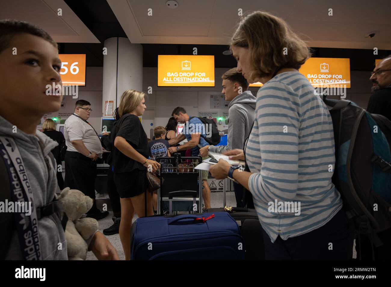 Junge Familie, die ihr Gepäck vor dem Flug mit der EasyJet Low-Cost-Fluggesellschaft am Abflugterminal von Gatwick North abgibt Stockfoto