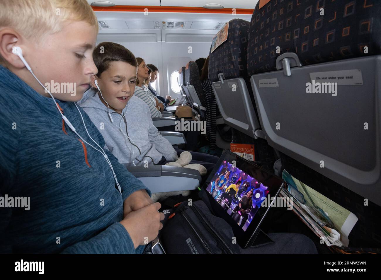 Junge Familie auf dem iPad, die sich einen Film anschaut, während sie mit der EasyJet Low-Cost-Fluggesellschaft fliegt Stockfoto
