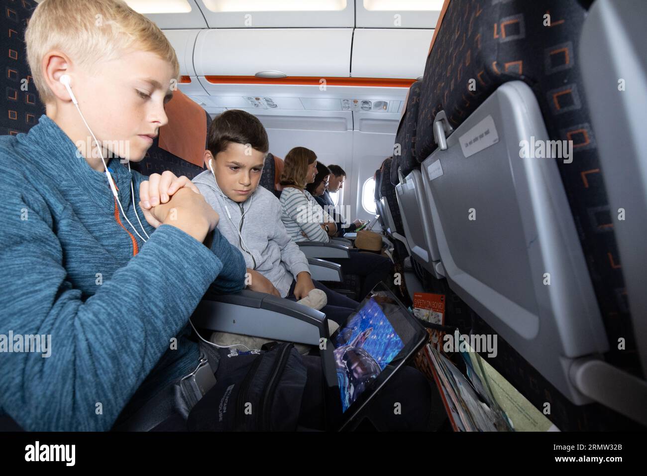 Junge Familie auf dem iPad, die sich einen Film anschaut, während sie mit der EasyJet Low-Cost-Fluggesellschaft fliegt Stockfoto