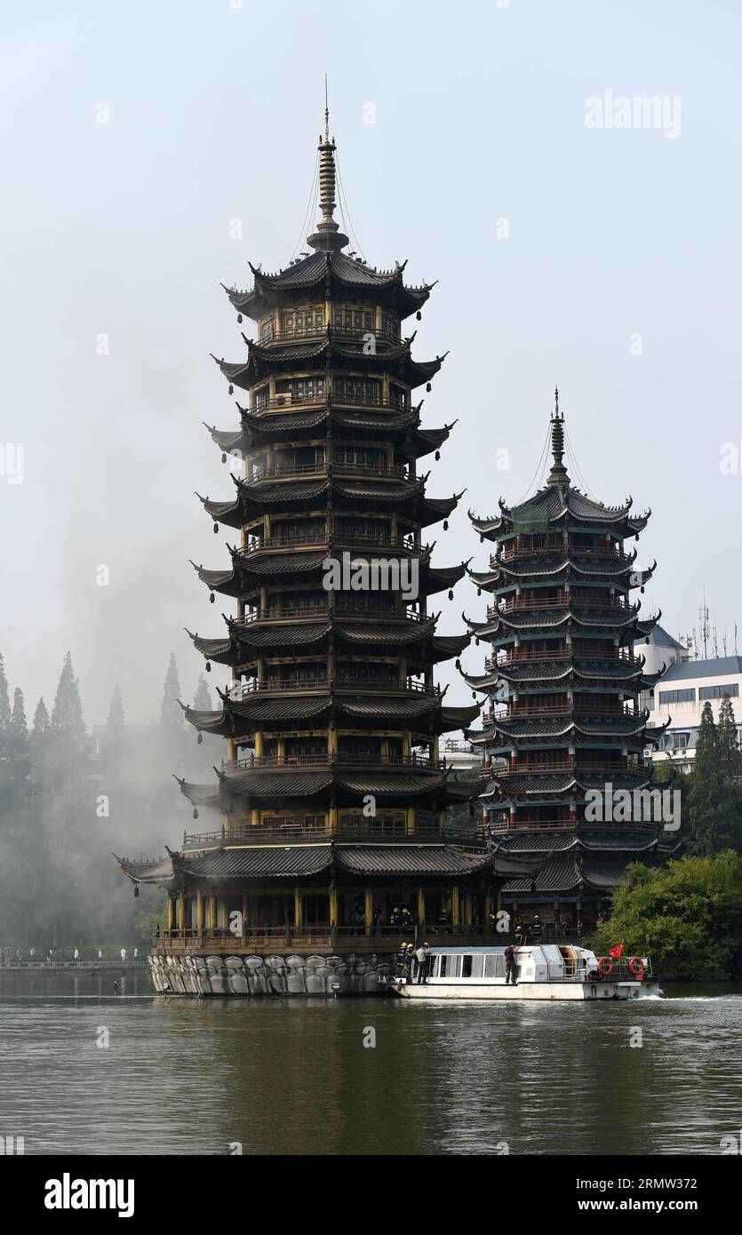 (141001) -- GUILIN, 1. Oktober 2014 -- Foto aufgenommen am 1. Oktober 2014 zeigt die Sonnenpagode, die im Tannensee in Guilin, der südchinesischen autonomen Region Guangxi Zhuang, Feuer fängt. Die bronzefarbene Betonpagode, die 41 Meter hoch war und aus 350 Tonnen Bronze bestand, fing am Mittwochmorgen Feuer. Die Feuerwehrleute setzten das Feuer ab, das mehr als zwei Stunden gedauert hatte. Die Doppelpagoden, genannt Sonne und Mond im Tannensee, wurden 2001 auf der Grundlage von etwas aus der Tang-Dynastie (618-907 n. Chr.) wiederaufgebaut. Sie gehören zu den touristischen Sehenswürdigkeiten von Guilin. ) (lfj) CHI Stockfoto