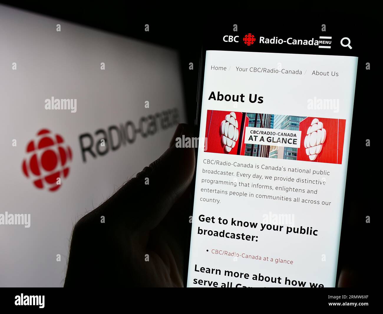 Person, die ein Mobiltelefon mit einer Webseite des öffentlich-rechtlichen Senders Radio-Canada (CBC) auf dem Bildschirm vor dem Logo hält. Konzentrieren Sie sich auf die Mitte der Telefonanzeige. Stockfoto