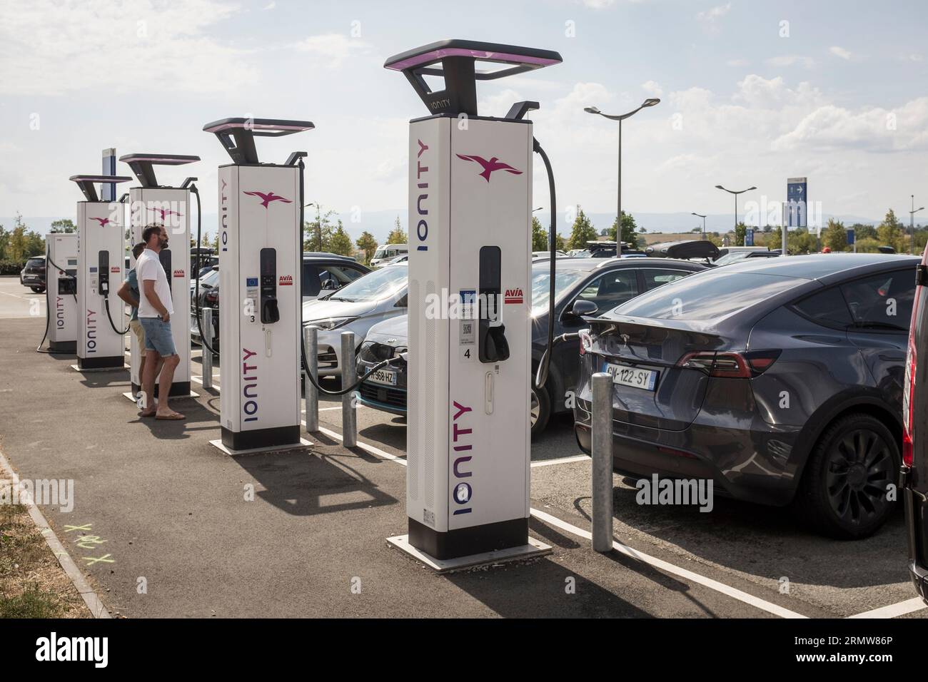 Leute, die warten, während ihr Elektroauto an einer Ionity-Ladestation an einer Autobahnraststation in Zentralfrankreich auflädt, 13. August 2023. IONITY ist ein Netz von Hochleistungs-Ladestationen für Elektrofahrzeuge zur Erleichterung des Fernverkehrs in ganz Europa. Es handelt sich um ein Joint Venture, das von der BMW Group, der Mercedes-Benz Group, der Ford Motor Company und der Volkswagen Group gegründet wurde. Andere Automobilhersteller sind jedoch eingeladen, das Netzwerk auszubauen. Stockfoto