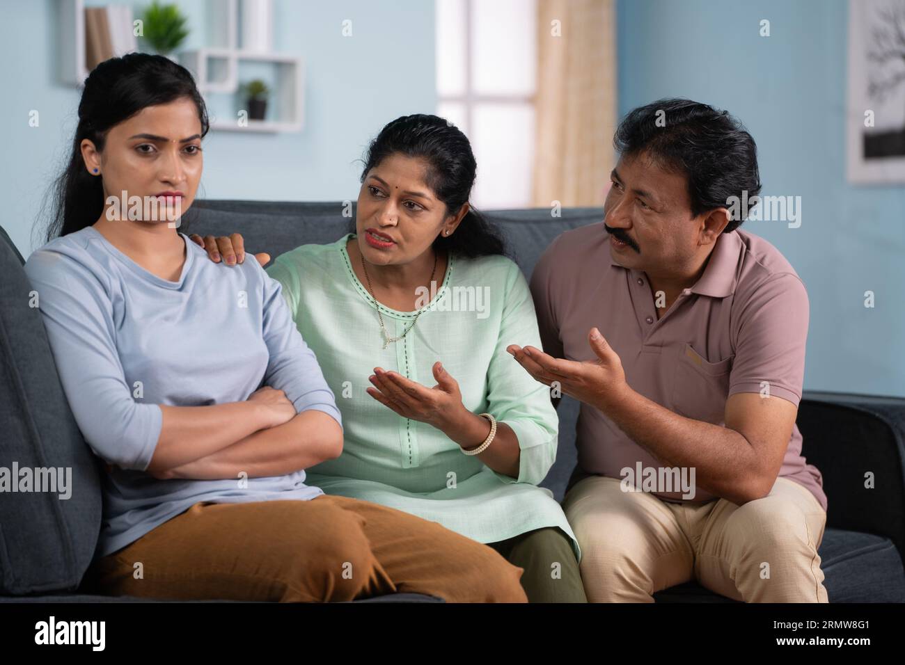 Konzentrieren Sie sich auf Eltern, indische Eltern, die nach einem Streit traurige oder wütende Tochter trösten, während sie zu Hause auf dem Sofa sitzen - Konzept der familiären Bindung, emotional Stockfoto