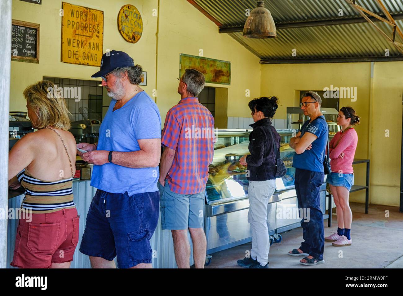 Kunden, die in einer Bäckerei in der Wüstenstadt Solitaire in Namibia anstehen. Bekannt für seinen berühmten Apfelkuchen Stockfoto