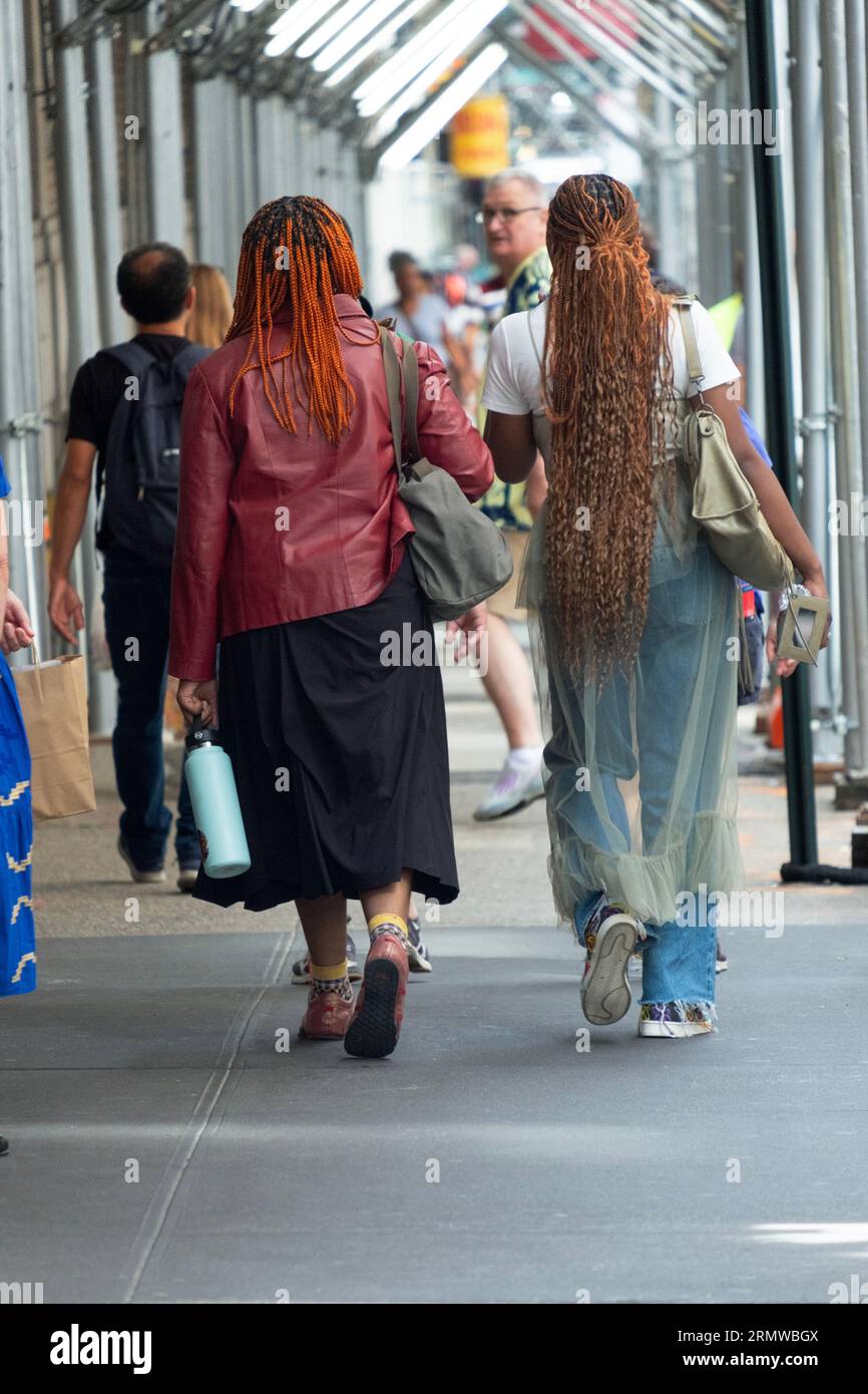 Zwei anonyme Frauen mit langen Haarverlängerungen auf der West 38th Street in Manhattan. Stockfoto
