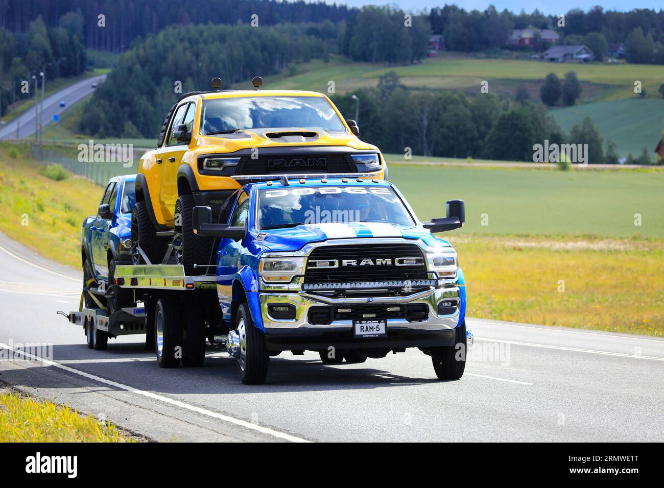 Der leistungsstarke und maßgeschneiderte RAM 5500-Lkw transportiert zwei Pickup-Lkw, einen gelben RAM und einen 3. Leichten Lkw auf Anhänger. Highway 3, Finnland. August 2023. Stockfoto