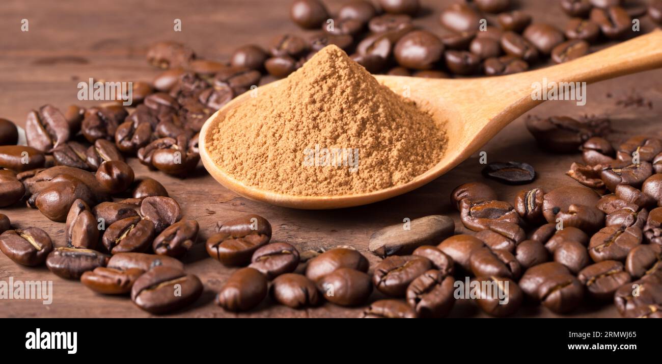 Löffel mit Pulver und Kaffeebohnen auf altem Holzlöffel Stockfoto
