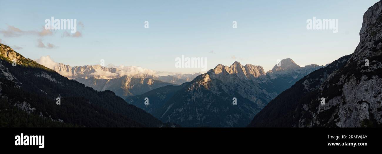 Weites Bild von wunderschönen hohen Felsenbergen mit Gipfeln, die von der untergehenden Sonne beleuchtet werden. Stockfoto