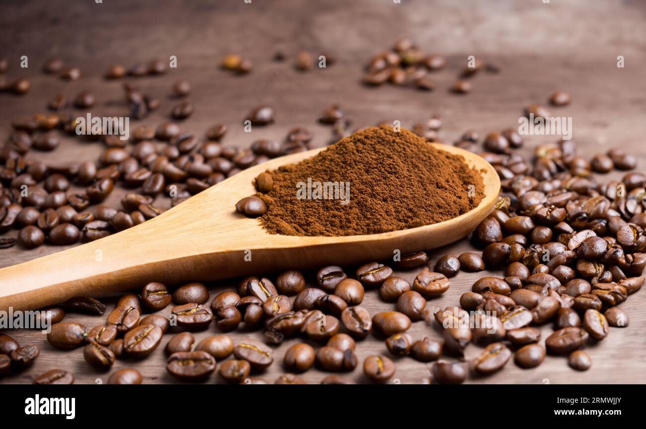 Löffel mit Pulver und Kaffeebohnen auf altem Holzlöffel Stockfoto