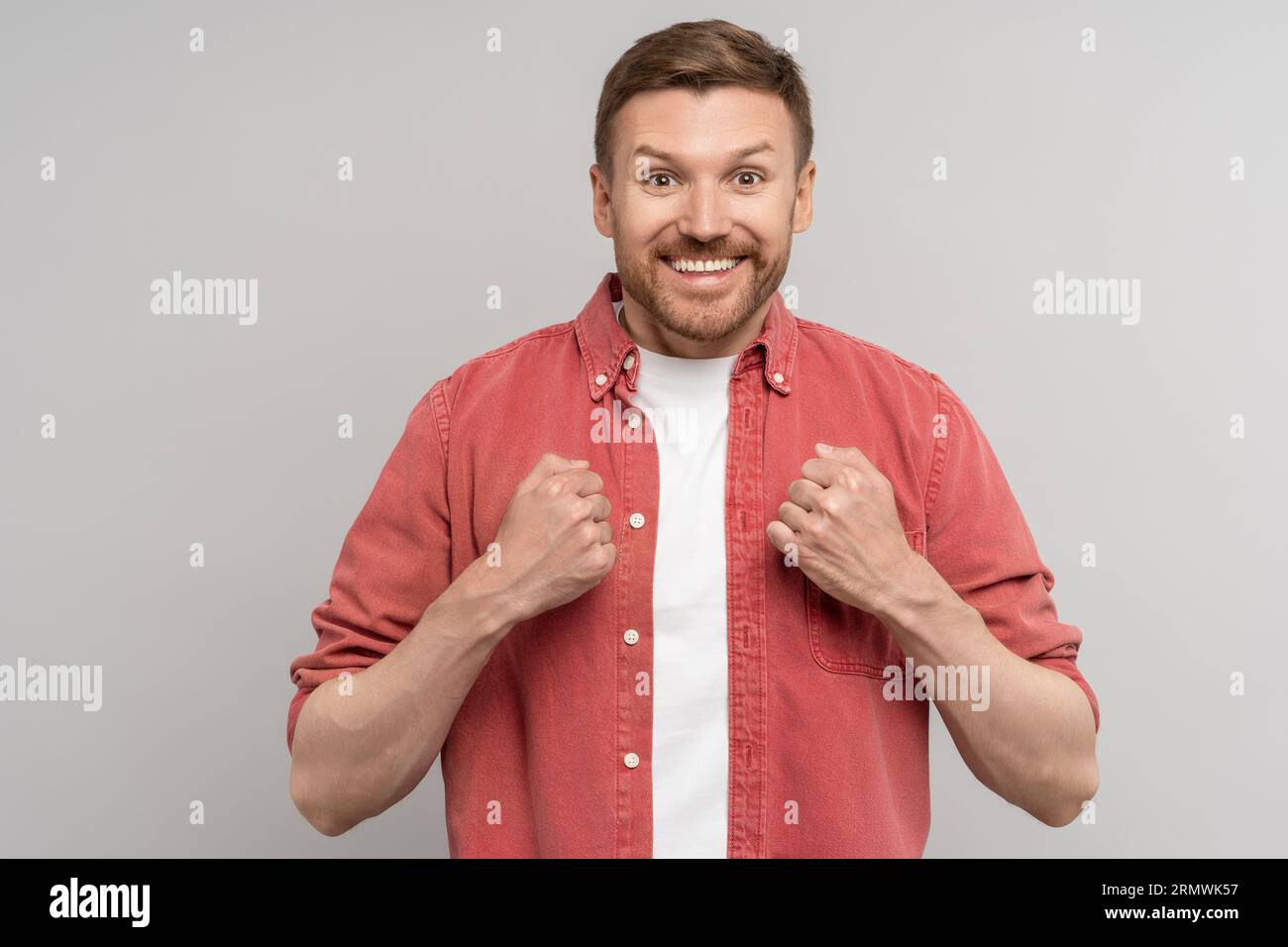 Aufgeregter überfreudiger Mann, der sich über unerwartetes Ergebnis freut, Fäuste hält, isoliert auf Studiohintergrund. Stockfoto