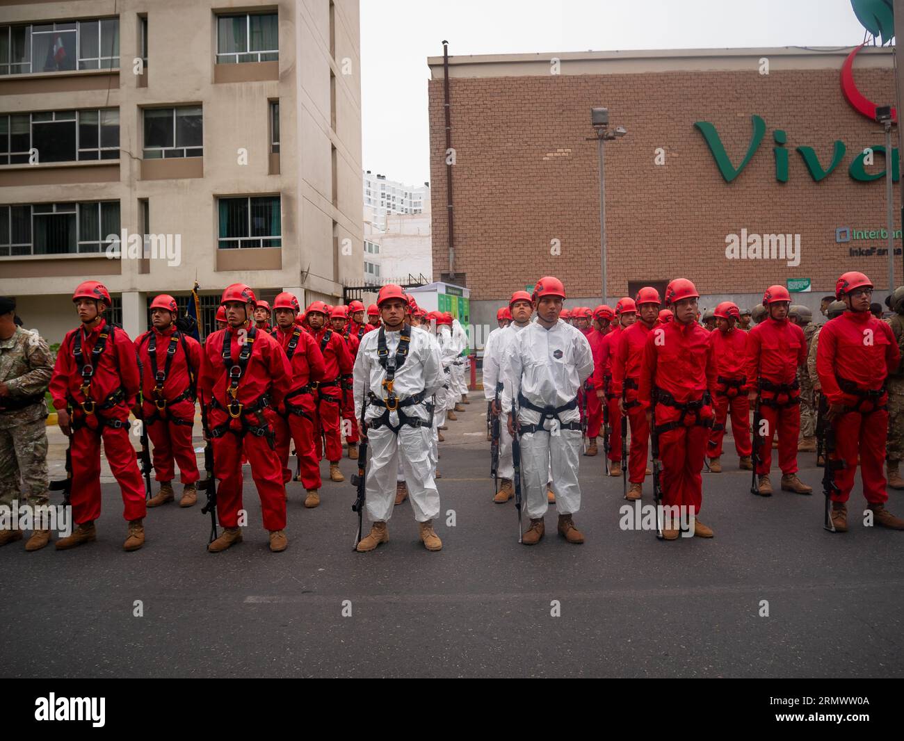 Lima, Peru - Juli 29 2023: Junge peruanische Männer in roten oder weißen Uniformen und Helmen marschieren als Feuerwehrmänner bei der Militärparade am Unabhängigkeitstag Stockfoto