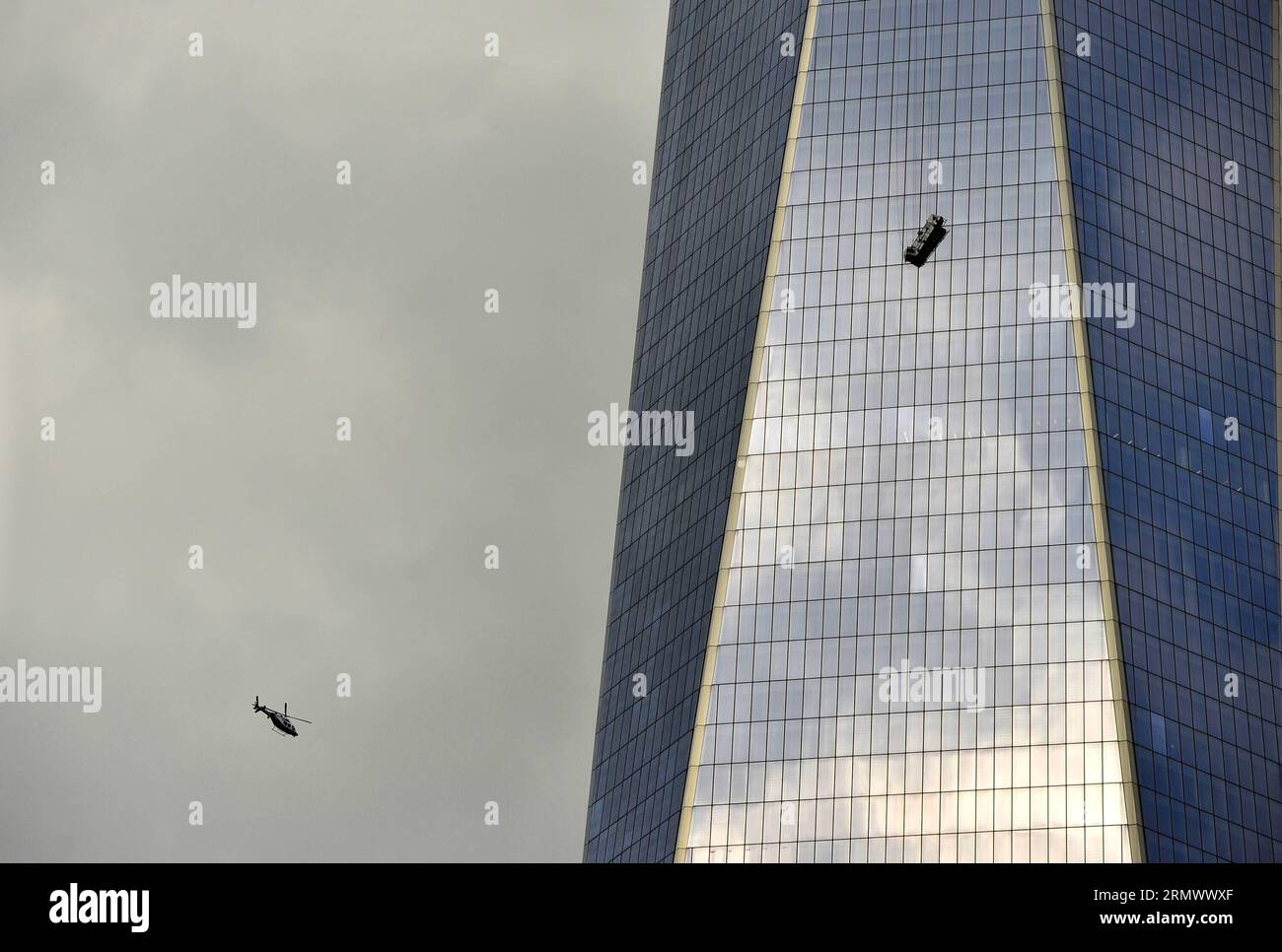 (141112) -- NEW YORK, 12. November 2014 -- Ein Hubschrauber fliegt herum, als ein Gerüst zwei Fensterscheiben trug, die hoch über der Oberfläche des One World Trade Center in New York, den Vereinigten Staaten, am 12. November 2014 herabhängten. Zwei Fensterscheiben waren am Mittwoch eine Stunde lang auf einem Gerüst gefangen, das hoch über der Fassade des One World Trade Center, dem höchsten Gebäude der westlichen Hemisphäre, herabhängte. Feuerwehrleute schnitten durch ein Fenster im 69. Stock nach oben und zogen sie vorsichtig in Sicherheit. ) US-NEW YORK-ONE WORLD TRADE CENTER-ACCIDENT-WINDOW-WASCHERS WangxLei PUBLICATIONxNOTxINxCHN New YORK Nov 12 2014 A Helicopte Stockfoto