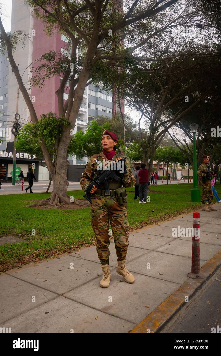 Lima, Peru - Juli 29 2023: Eine peruanische Frau in Tarnkleidung, Wanderschuhen und einem roten Baskenmütze trägt eine Waffe beim Militar zum Unabhängigkeitstag Stockfoto