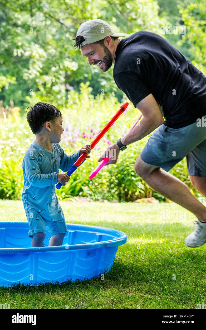 Vater und Sohn spielen an einem heißen Sommertag mit Wasserspielzeug Stockfoto