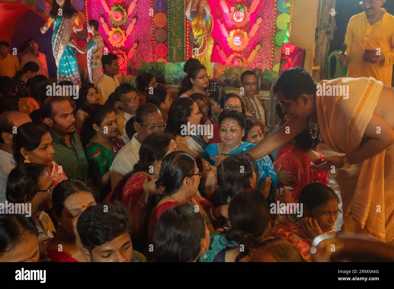Howrah, Westbengalen, Indien, 3. Oktober 2022: Hindu purohit zeichnet tilak, heiliges Zeichen auf der Stirn von Hindu-Gläubigen, die Göttin Durga anbeten. Stockfoto